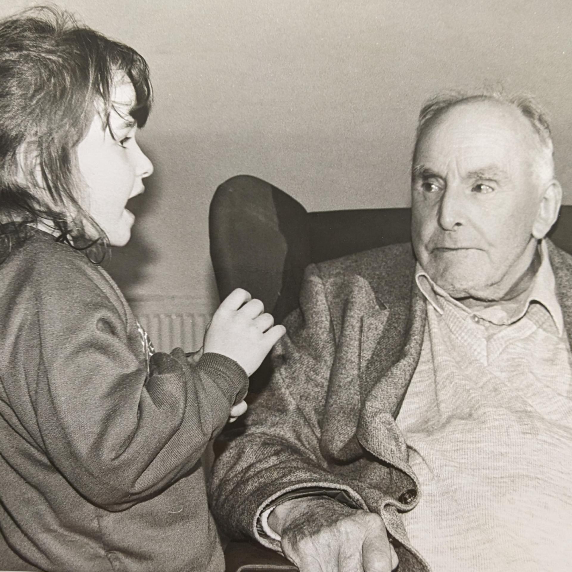 black and white image of a child and old man sat on a chair